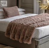 A plush dusky pink faux fur throw with a ribbed texture draped over the bed for cozy style