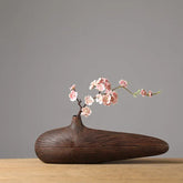 Dark brown ceramic kabin vase with radial grooves and slender neck holding pink cherry blossoms
