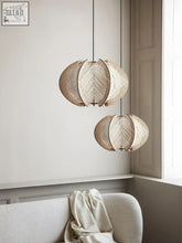 Two beige leaf-shaped kazaru light pendant lights with woven wooden texture hanging from black cords