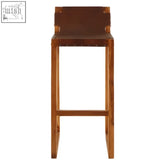 Kendari brown leather bar chair with teak wood frame featuring brown leather top and wooden legs with metal rivets