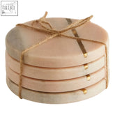Stack of six round beige marble coasters tied with twine paired with kira set of 4 pink marble coasters with gold inlay