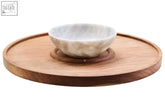 A white marble chip bowl with gray veining on a kora acacia wood circular serving tray for chip and dip use
