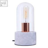 A sleek lamonte bell lamp with a clear glass dome copper base and grey marble base for stylish lighting