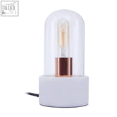 Lamonte bell lamp with white marble base features a sleek ceramic base and clear dome housing an exposed filament bulb