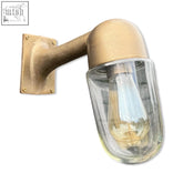 Industrial-style raw antique brass wall sconce with clear glass and exposed filament bulb for outdoor or bathroom use