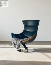 Elegant navy blue leather lobster lounge chair with sleek wooden accent and chrome base draped in houndstooth throw