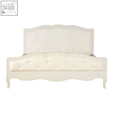 Cream-colored tufted upholstered white super kingsize bed with ornate carved wooden frame and curved legs