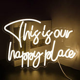 A glowing white neon happy place neon sign in cursive perfect for wall decor in bedroom kids room and party spaces