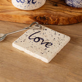 Love single stone coaster with white speckled natural limestone, dark blue love script, heat resistant with silver heart hook