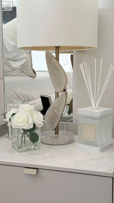 A sleek luxury square diffuser rosa blanco with a white rose scent and gold leaf-shaped metallic accents on base