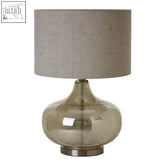 A sleek mercury glass table lamp with a textured finish and a neutral grey fabric shade