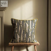 A magic beans cushion with cream base, navy blue and olive green paisley bands, and bright yellow trim