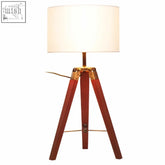 Malvern tripod table lamp with brown base features a warm wooden tripod and cream fabric shade with brass accents