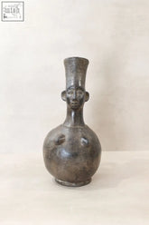 A dark matte mangbetu clay pot shaped like a stylized human figure from the democratic republic of congo