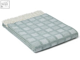 A soft light blue manhattan pure new wool throw with intricate square pattern and cream fringe edge inspired by manhattan skyline
