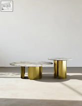 Two minimalist nesting coffee tables with white sintered stone tops and polished gold cylindrical legs from maru set