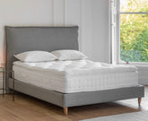 Gray upholstered double bed with luxury pillow top mattress and matching white quilted pillows