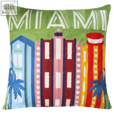 A vibrant miami needlepoint cushion with embroidered colorful buildings on emerald green fabric perfect for home decor