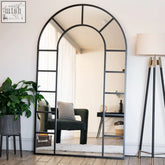 Arched full length mirror with black metal arched frame and multiple rectangular glass panes for wall decor