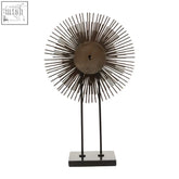 Bronze sunburst wall clock with slender metallic rays and central keyhole paired with black quill sculpture design