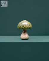 A translucent green moss mushroom with a textured preserved moss cap and speckled pinkish brown light stone stem