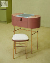 A sleek rose-pink muskoka dressing table set with glass top and gold-tone metal legs for stylish grooming