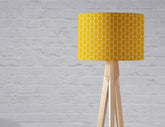 Mustard yellow table lamp with white geometric design on a light wood tripod base perfect for cozy lighting
