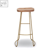 A rustic nandri acacia wood bar stool with a round seat and slender antique brass bar legs