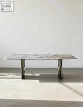 A sleek natural marble dining table with a gray marble top and polished chrome legs that adds modern style