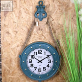 Teal nautical wall clock with white face black numerals and hands hanging by thick rope for a nautical wall look