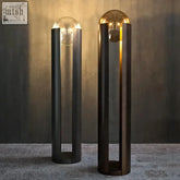Two norda lamps with black cylindrical bases and glass globe features glowing light bulbs shine as modern desk lamps
