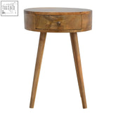 A nordic circular shaped bedside table in oak mango wood with a round top, single drawer, and tapered legs