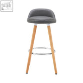 Gray upholstered bar stool with light wood legs and chrome footrest perfect for a grey bar or kitchen counter