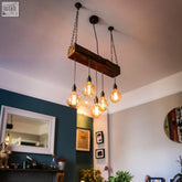 Rustic oak beam chandelier with five exposed filament bulbs hanging from black chains ideal for kitchen island lighting uk lead time info