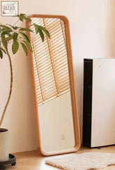 Okemia mirror is a tall rectangular mirror with a light curved wood frame reflecting wooden blinds