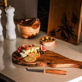 Rustic handcrafted olive wood cheese knife with natural edge and dark grain pattern perfect for serving cheese