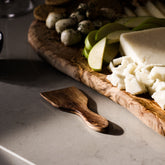 Rustic olive wood raclette spatula with smooth polished finish and natural grain patterns for cheese spreading