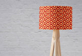 Rectangular table lamp with orange and brown circles design lampshade on light wood tripod lamp base with inch diameter