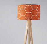 Orange lampshade table lamp with white hexagon design on light wood tripod base for ceiling or table use