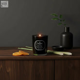 Black magic scented candle in black glass jar with lit flame and silver orange and lemongrass label coreless clean burn