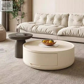 Cream-colored round orbit coffee table with sleek minimalist design and subtle front drawer modern coffee table