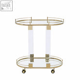 Oria drinks trolley with warm gold metallic frame clear acrylic legs glass shelves and modern two-tier design on wheels
