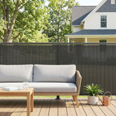 Woven rattan outdoor sofa with light gray cushions next to dark grey outsunny windbreak fence screen fence panel