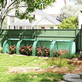 Green outsunny tunnel greenhouse with steel frame and zipped doors protecting backyard flowering plants