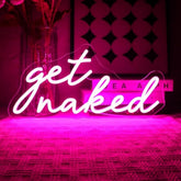 A glowing pink led neon light sign with white cursive get naked text for bedroom home bar decoration