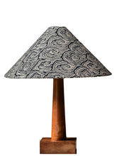 A large tapered cone lampshade with a black and white swirling pattern on a slender wooden stand