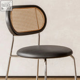 Ozzie rattan dining chair with black leather seat and backrest featuring woven cane panel and chrome legs