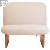Cream linen textured armless chair with a wood base and cream-colored upholstery perfect for lounging
