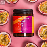 A passionfruit martini apothecary candle in a dark amber glass jar with a colorful label and sustainably sourced soy wax