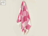 A soft pastel block check merino lambswool throw in pink and white with fringed edges perfect for cozy nights